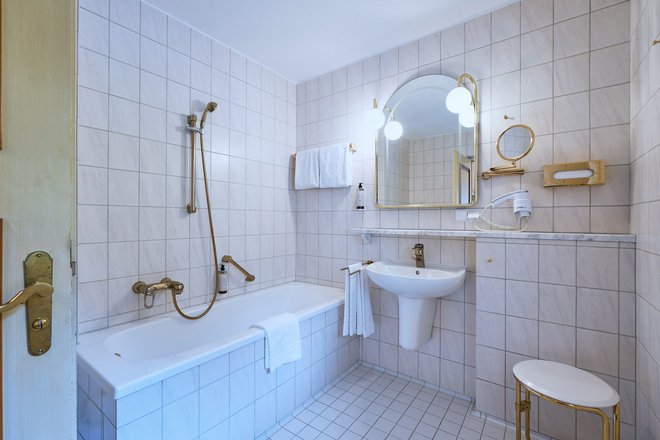 Beispielbild eines Badezimmers im Hotel Müller in hellen Fließen inklusive Badewanne und Wachbecken